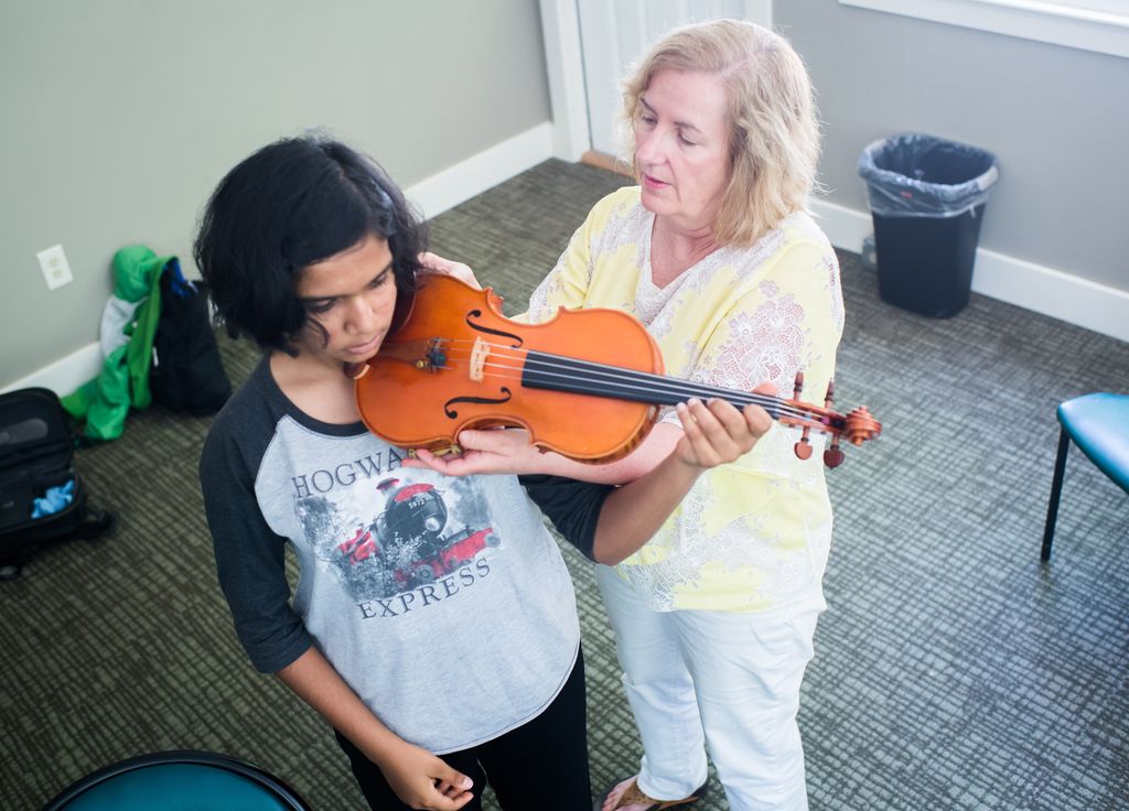 Physical therapist Regina Campbell adjusts the way a student is holding her violin