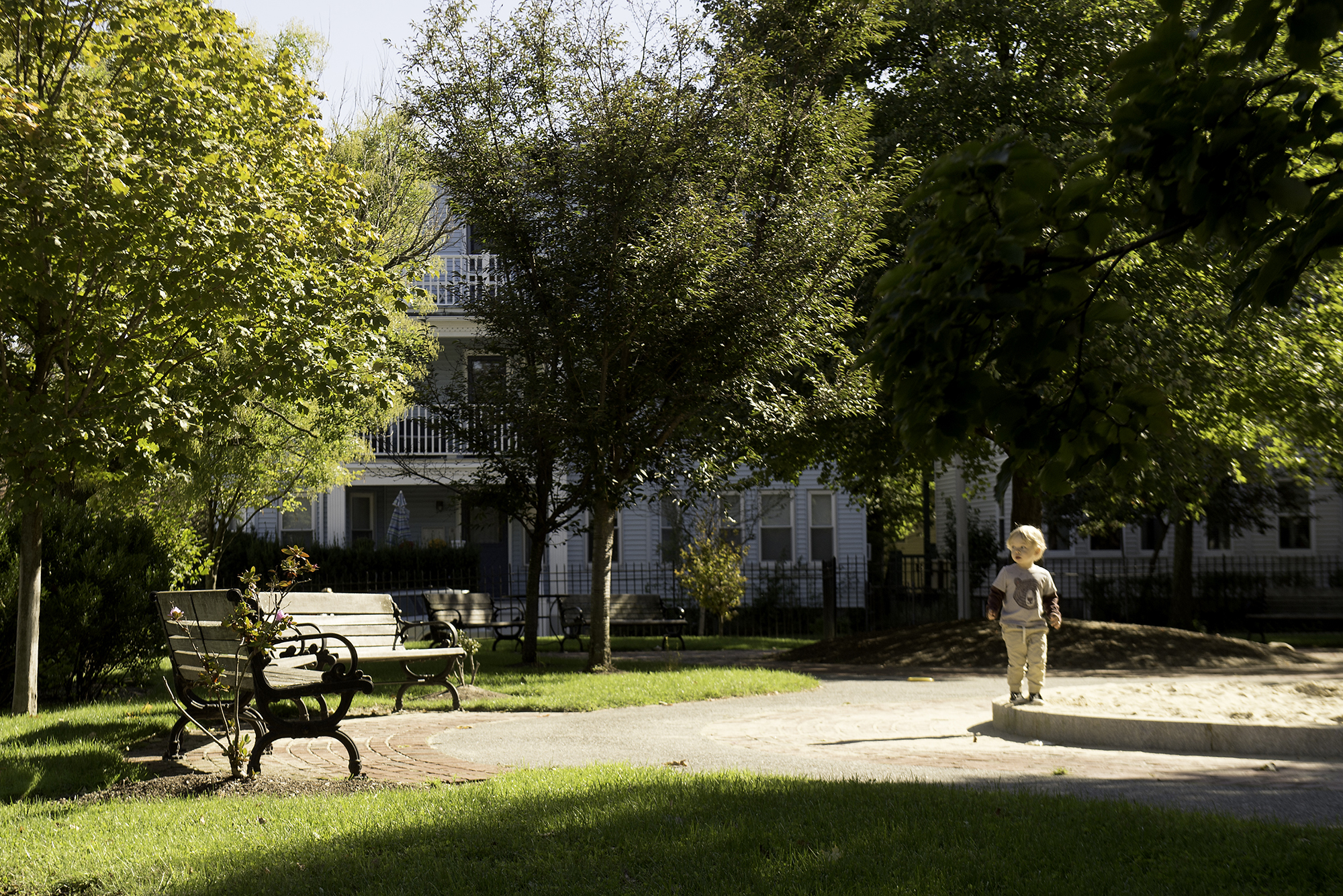 Photo of Linden Park. A picturesque park featuring benches, a sandbox, and a small child are shown.