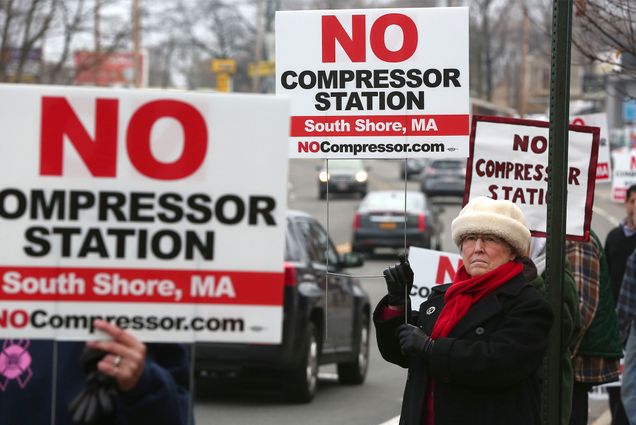 People hold signs protesting a proposed natural gas compressor station in Weymouth, Massachusetts.