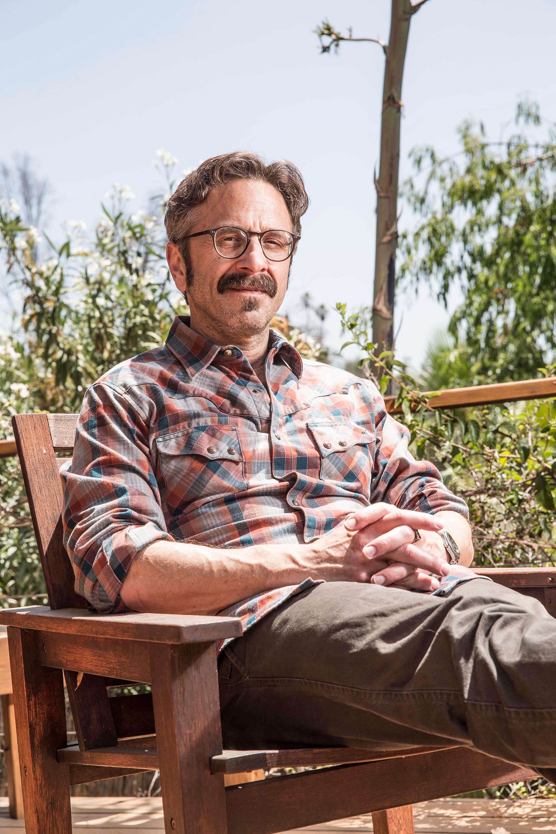 Portrait of comedian and WTF podcast host Marc Maron sitting on an outdoor patio.