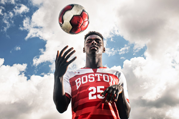 George Abunaw wears his red Boston University soccer jersey as he tosses a ball in the air