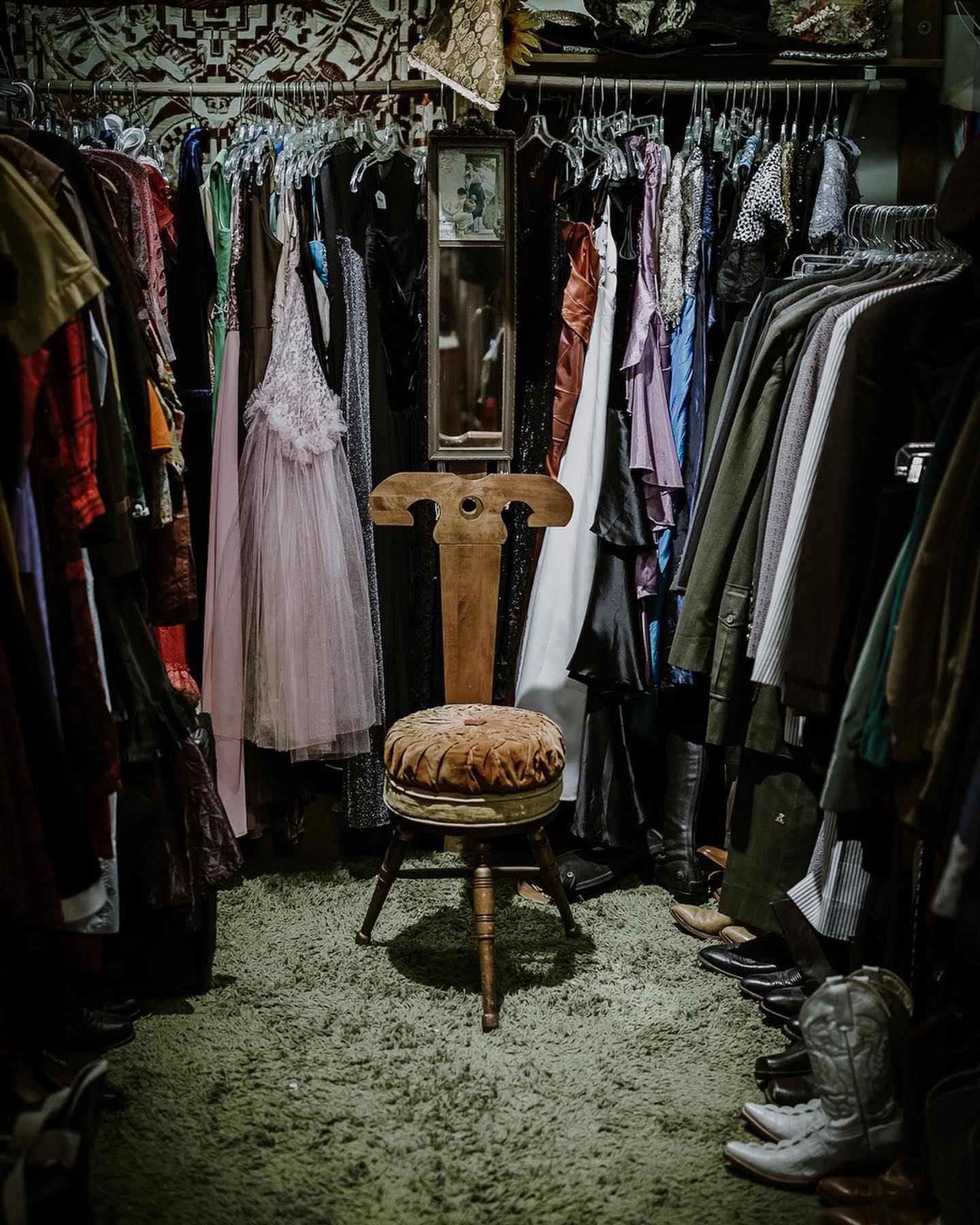 A unique chair is surrounded by hanging clothes in the Great Eastern Trading Co.