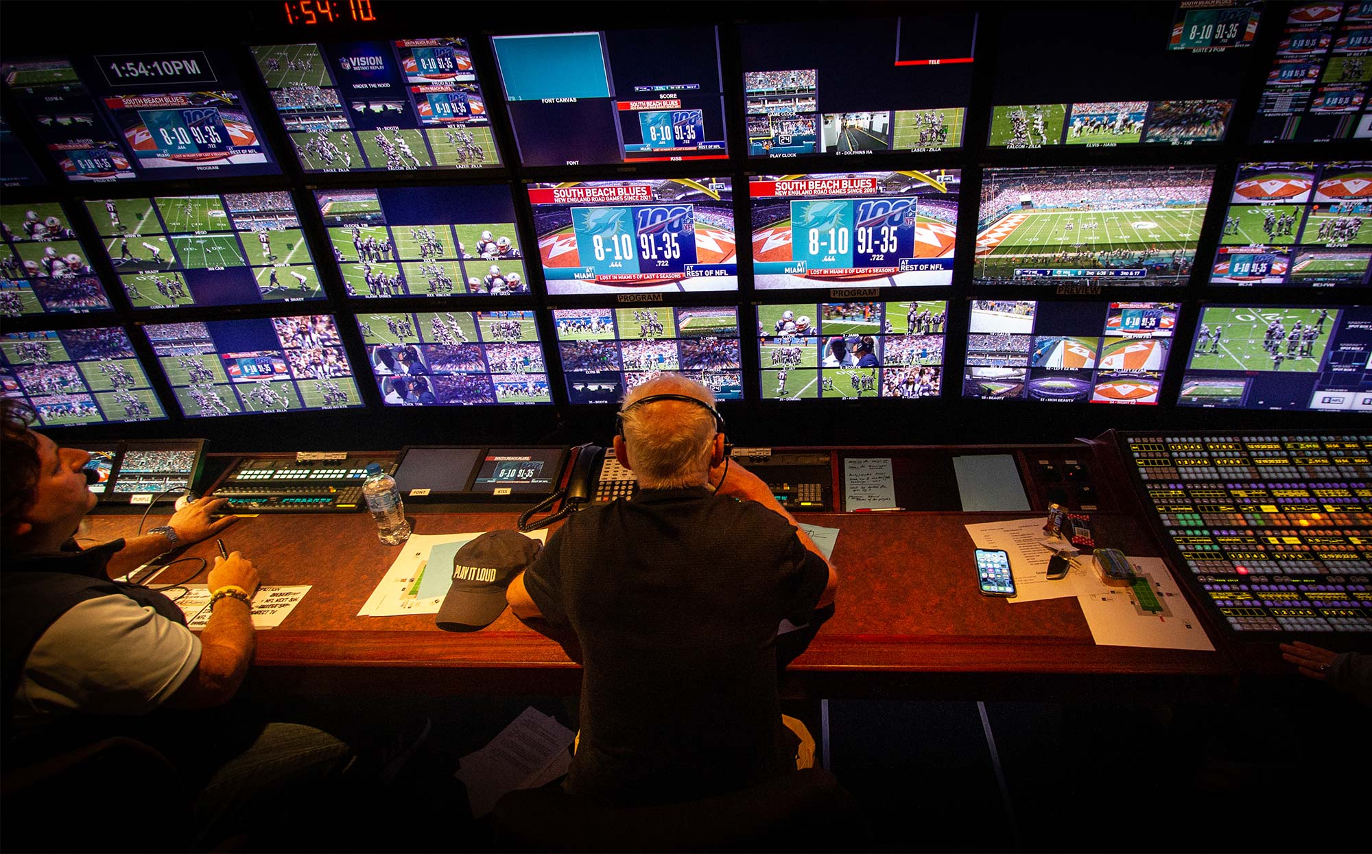 View over the shoulders of sports broadcasting director Bob Fishman watching the screens in the truck while directing an NFL broadcast