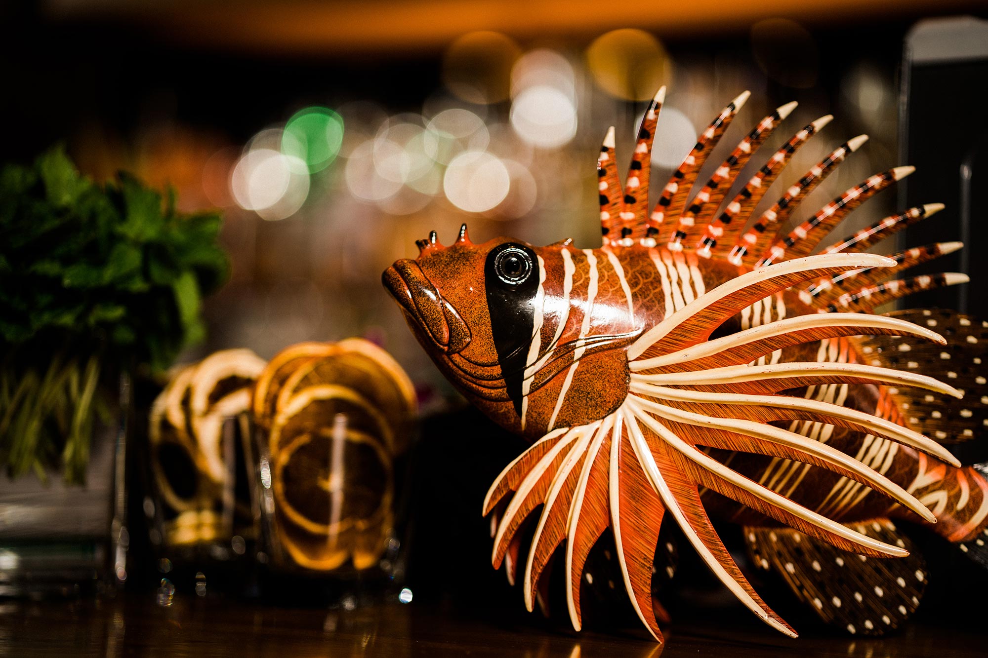 A red scorpion fish tiki decoration and cut fruit for making cocktails on the bar at Shore Leave Boston tiki bar.