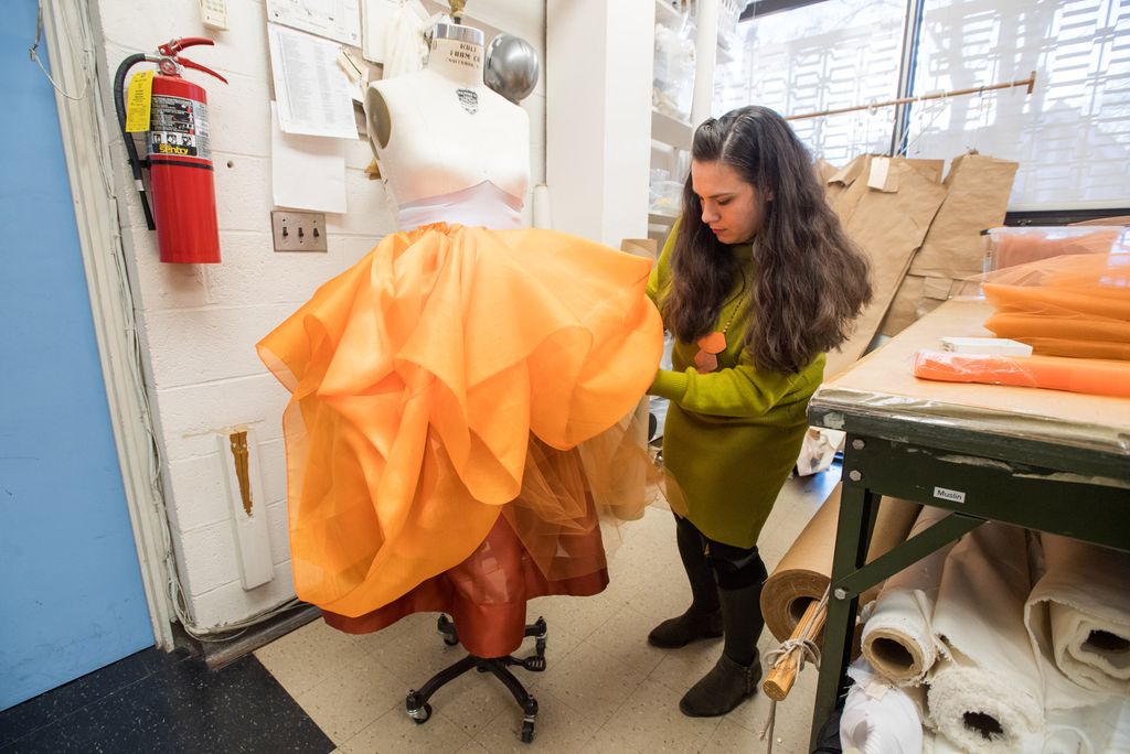 Kerl works on draping orange tulle to create a skirt