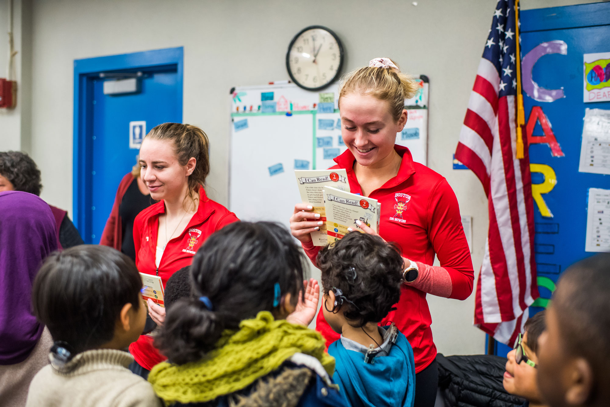 Members of the Women's Rowing team including, Kate Horton (left) (CAS 19) and Grace Beery (CAS 21) hand out book to students at Horace Mann Elementary School on Friday, December 13, 2019.