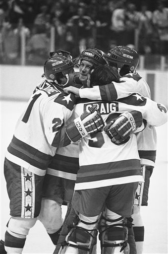 In this Feb. 22, 1980 file photo, Michael Eruzione, left, scorer of the decisive fourth goal for the USA in the Miracle on Ice game against USSR in Lake Placid, is embraced by team mates John O'Callahan, David Silk, and goalie James Craig after he brought his team into the lead.
