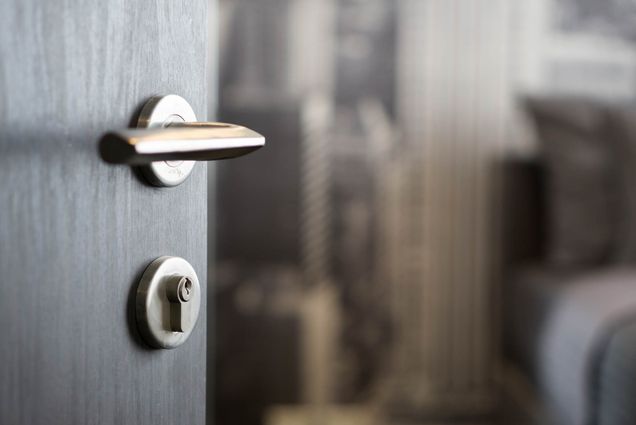A photo of an open door with an out-of-focus dorm room visible in the background.