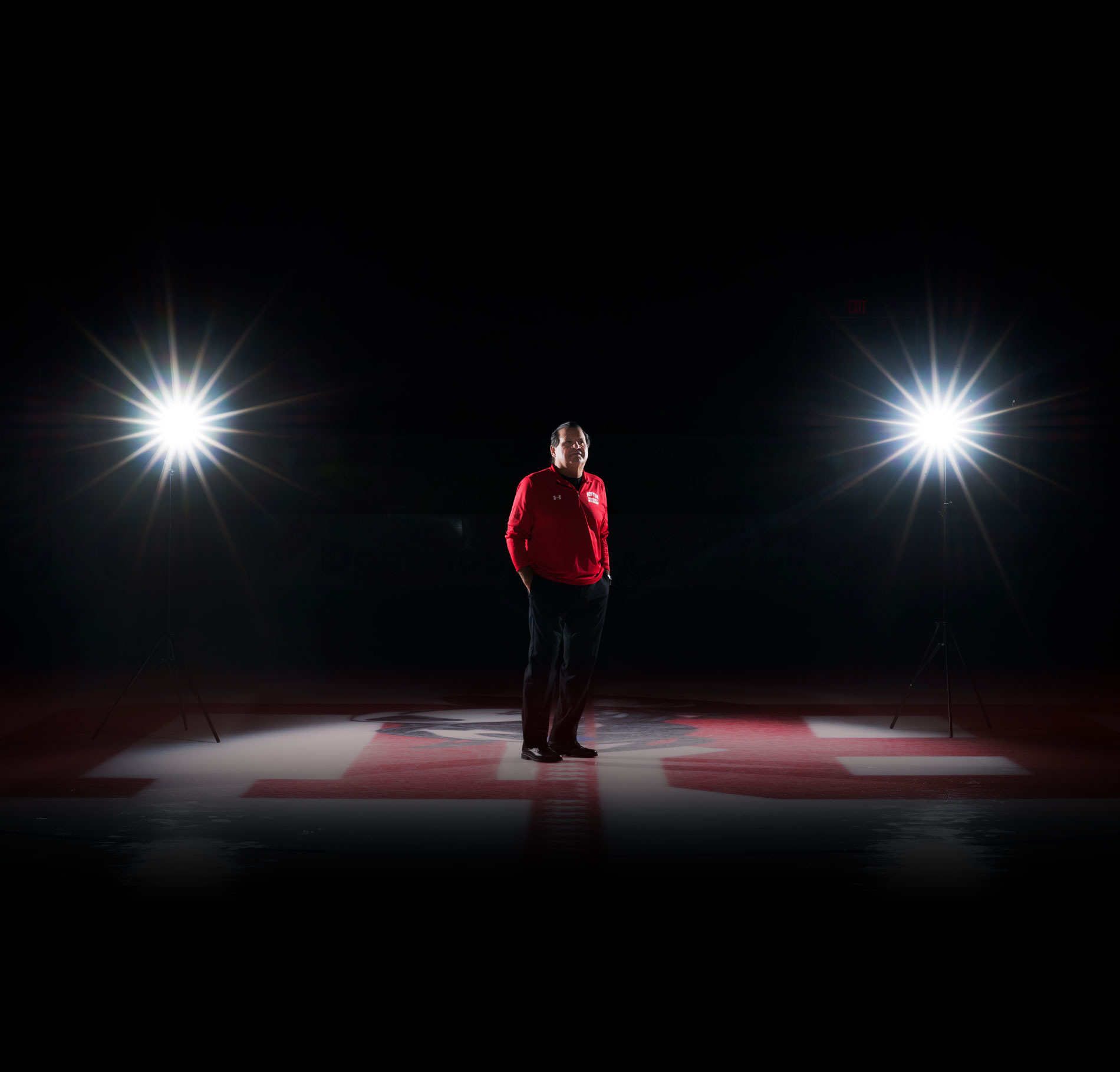 Portrait of Mike Eruzione standing at center ice in a hockey rink.