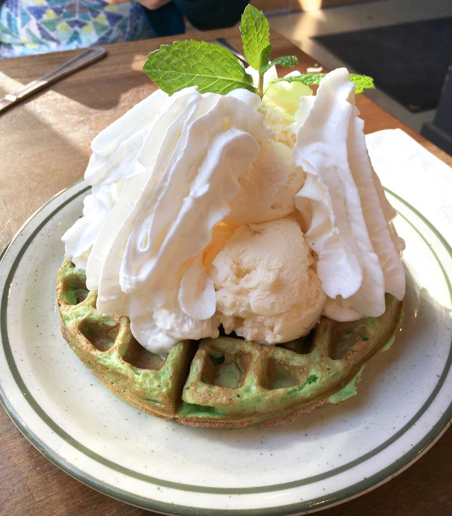 A green pandan leaf coconut milk waffle topped with vanilla ice cream.