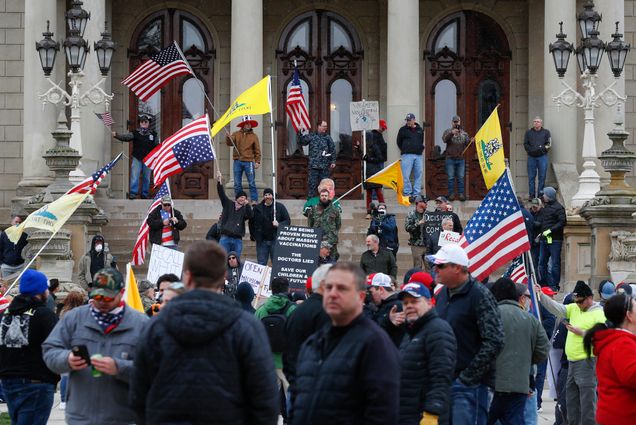 Protesters stand on the steps of the State Capitol in Lansing, Mich., Wednesday, April 15, 2020. Flag-waving, honking protesters drove past the Michigan Capitol on Wednesday to show their displeasure with Gov. Gretchen Whitmer's orders to keep people at home and businesses locked during the new coronavirus COVID-19 outbreak.