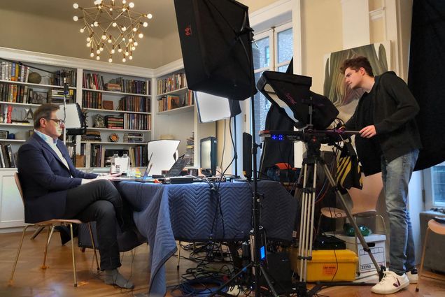 Photo of Nick Mason (COM’22) acting as a production assistant to his father, CBS This Morning co-host Anthony Mason, as they broadcast from their Manhattan apartment. Anthony is not wearing any shoes, and sits in front of a laptop with a suit jacket on.