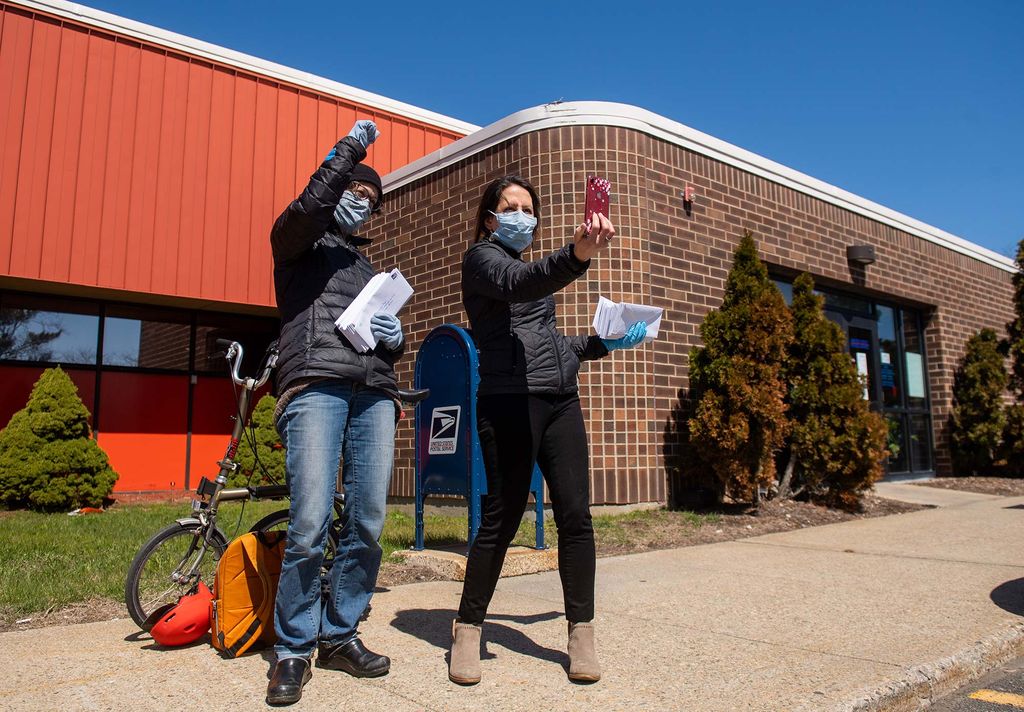Image taken outside a USPS office in Chelsea, where Madeleine Scammell, SPH epidemiologist, left, and Roseann Bongiovanni (CAS '99, SPH '01) broadcast a Facebook Live feed to the GreetRoots Facebook page April 23, 2020. The two, who are on the board at GreenRoots, were mailing out hundreds of checks to recipients of the One Chelsea Fund, which provides money to families effected by the COVID-19 crisis.