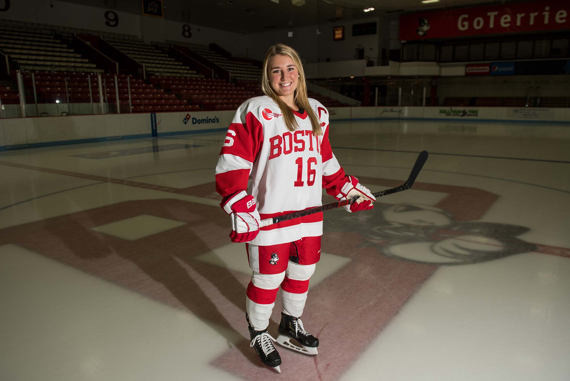 Portrait of Sammy Davis, BU women's ice hockey co-captain and no. 1 overall pick in the 2020 NWHL draft, on the ice at Walter Brown Arena at Boston University