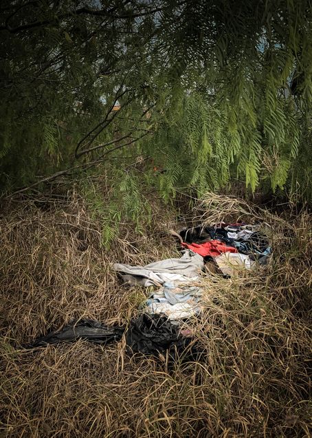A photo of clothes on the ground near the border wall