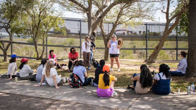 A photo of the group sitting on the ground in a semi-circle near the banks of the Rio Grande