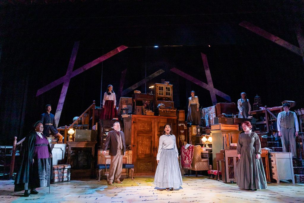 Martinez’s set design for Wheelock Family Theatre’s 2020 production of Little Women: The Broadway Musical. A group of individuals in 20th century clothing stand scattered across a stage on multiple levels.