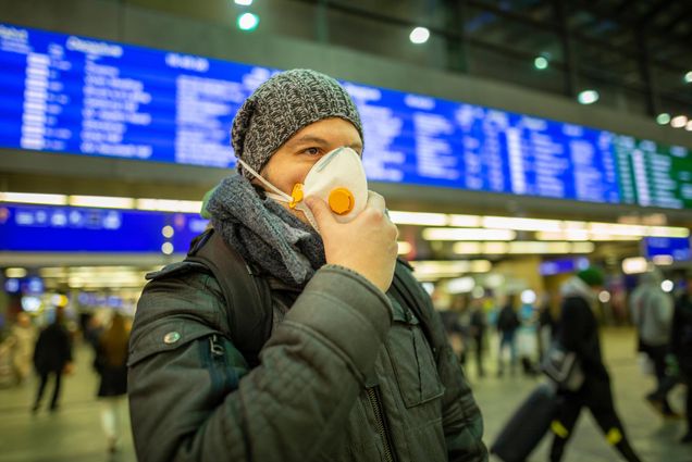 A photo of a man wearing a mask in a train station