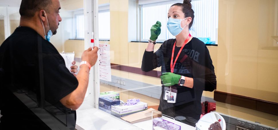 Emily Gibb offers testing advice to Ahmad Al Khafaji during a visit to the Boston University Medical Campus COVID-19 testing site