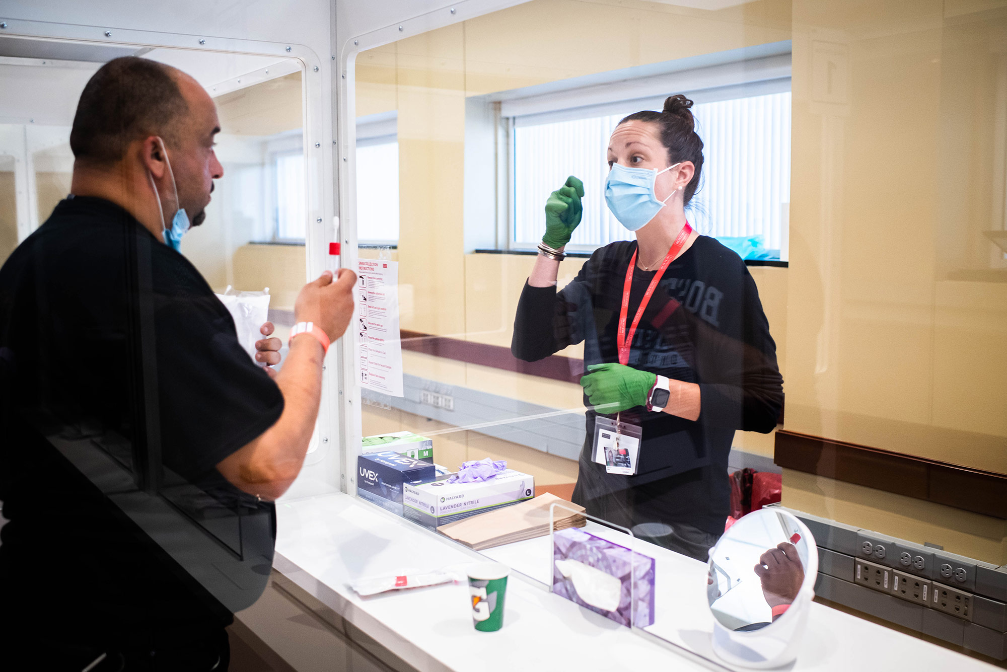 Emily Gibb offers testing advice to Ahmad Al Khafaji during a visit to the Boston University Medical Campus COVID-19 testing site