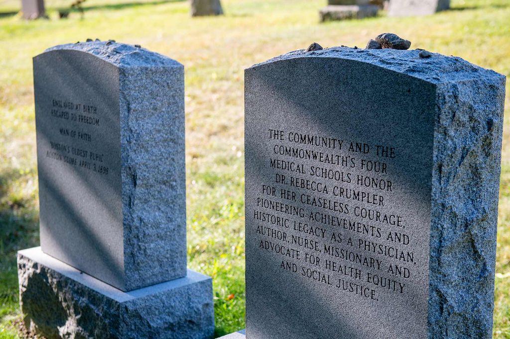 Back of the the headstones of Rebecca Lee Crumpler (MED'1864), the first Black woman to graduate from a medical college in the country, and her husband Arthuer Crumpler. The headstones are at the Fairview Cemetery in Hyde Park. Bright green grass grows around the headstones.