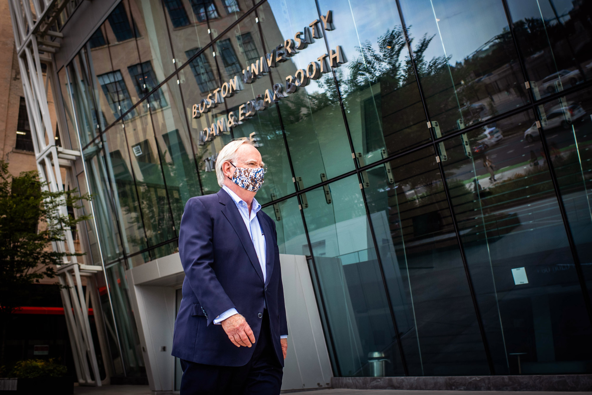 A photo of Robert Brown wearing a mask walking in front of the Booth theater.