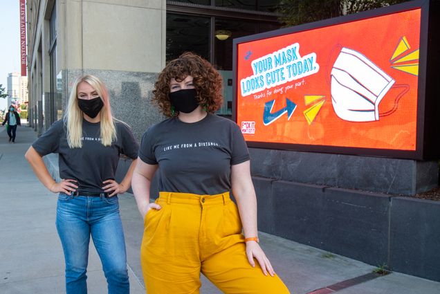 A photo of AdLab leaders Hailey McKee (COM’20), and Hannah Schweitzer (COM’21) in front of one of there campaign displays