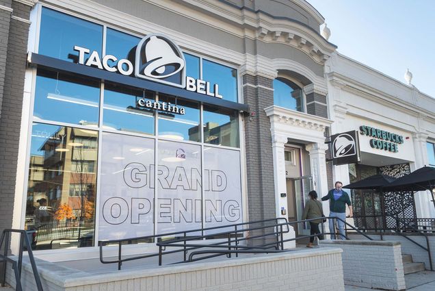 Photo of Bostonians entering the new Taco Bell at 872 Commonwealth Ave. which has been generating big buzz among students. Photo shows the facade of store, a large gray "GRAND OPENING" sign is seen in the storefront windows.