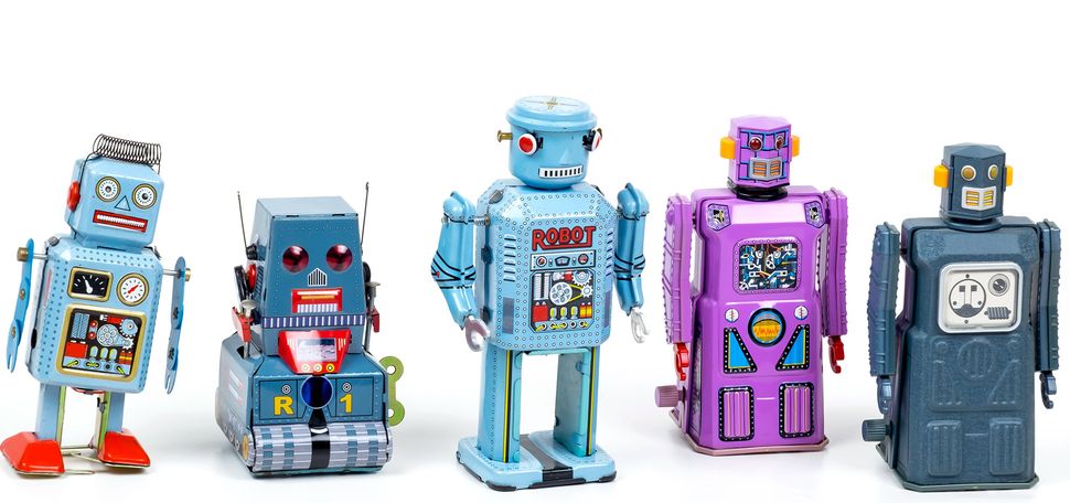 Photo of 5 different toy robots that are blue, light blue and purple, lined up on a white background.
