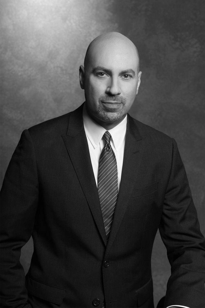 Black and white portrait of Gary M. Garfinkel (Questrom’84), who stands in a suit and tie.