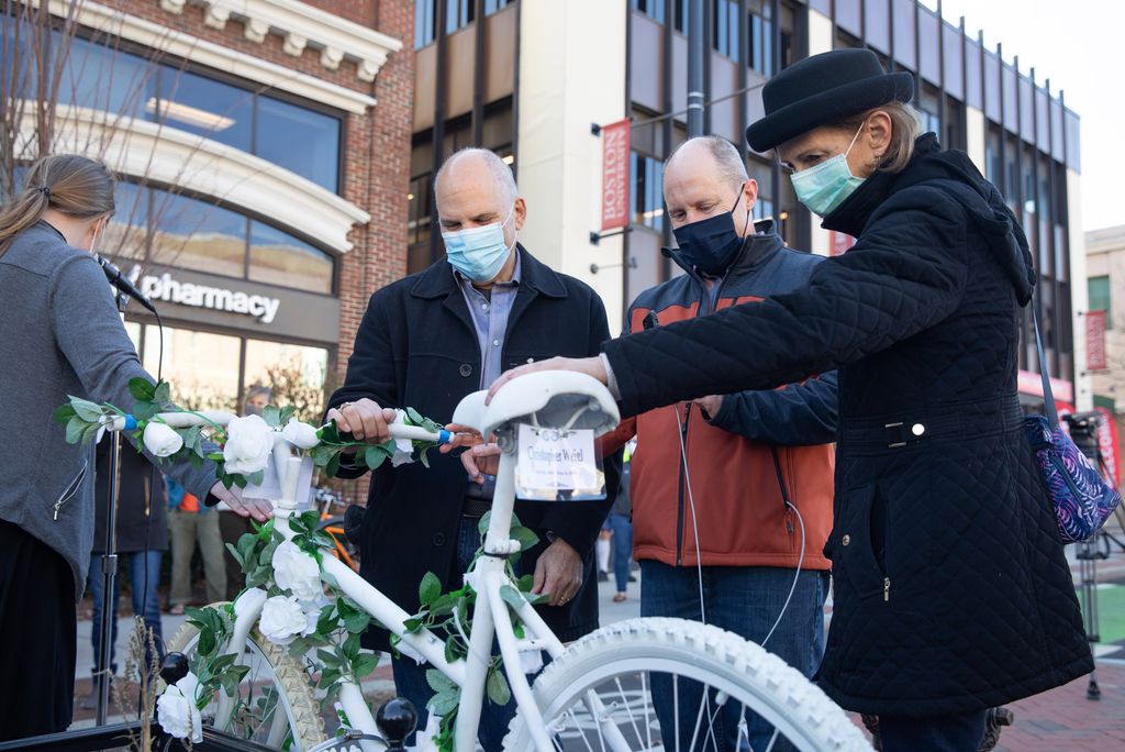 Andy Weigl, (left) and his wife Bonnie Weigl (right) pay tribute to their son Christopher's ghost bike during the Massachusetts Bicycle Coalition's memorial ghost bike installation ceremony Saturday, November 21, 2020 on the corner of Commonwealth Avenue and St. Paul Street in Boston in honor of Christopher Weigl (COM'14) who was killed by a truck driver on December 6, 2012.