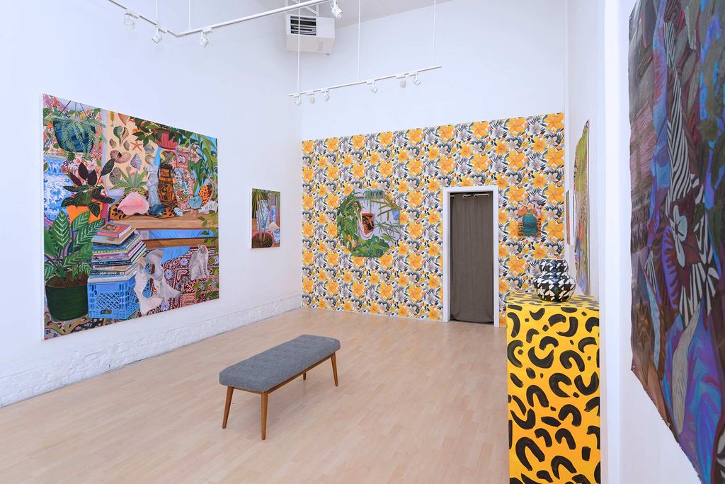 Objects of Affection, solo exhibition installation at Hashimoto Contemporary in San Fancisco, Calif. In a small white-walled room hangs a wallpaper around a door frame on the backwall; the pattern is bright green and yellow. On the left wall, a large, colorful painting of Valdez's hangs. In the right foreground, a table with a leopard print table cloth is seen.