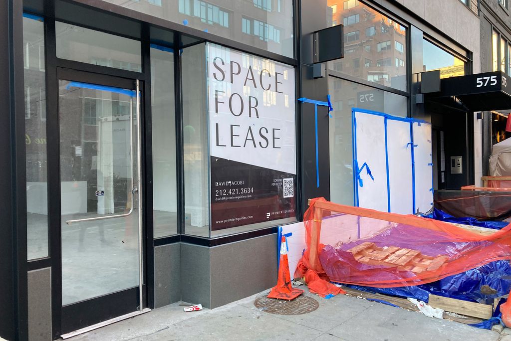 A photo of a sign reading "Space for Lease" in the window of a vacant storefront