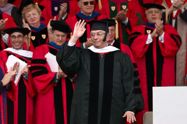 Photo of Jon Westling receiving an honorary Doctor of Humane Letters Degree in 2003. Westling wears a black robe and cap and waves with his right hand. A crowd of faculty in red regalia are seen behind him.