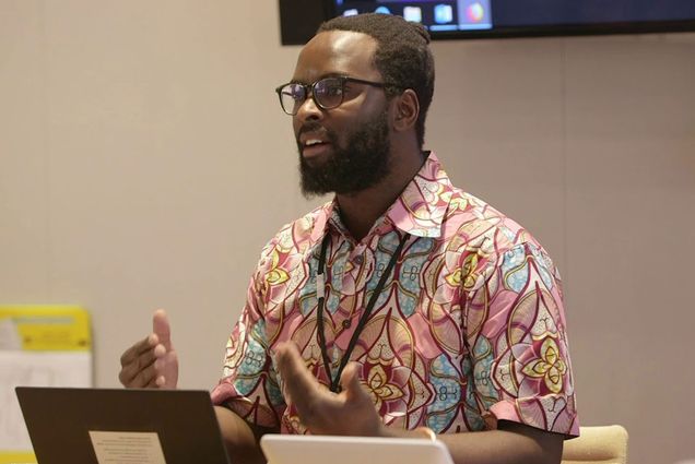 A photo of Sabelo Mhlambi speaking at a podium