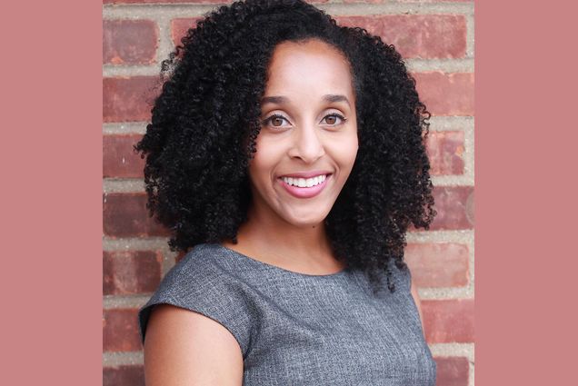 Headshot of Alexis Redman (Questrom’14), head of the BU Young Alumni Council, in a gray textured blouse, smiling as she stands in front of a brick wall. Photo is on a brick-colored solid background.