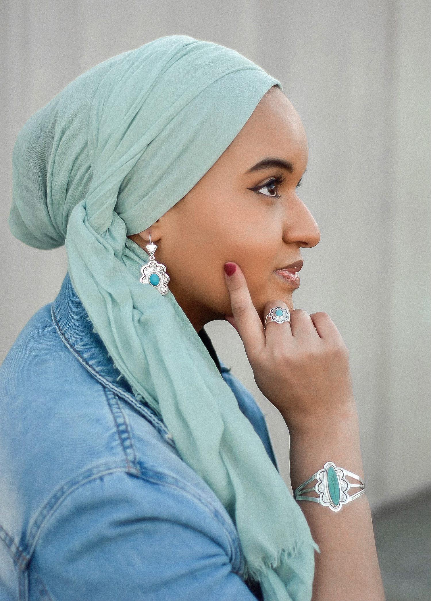 A photo of Malika Kounkourou holding her hand to her face in a pose that shows off her earring, ring, and bracelet