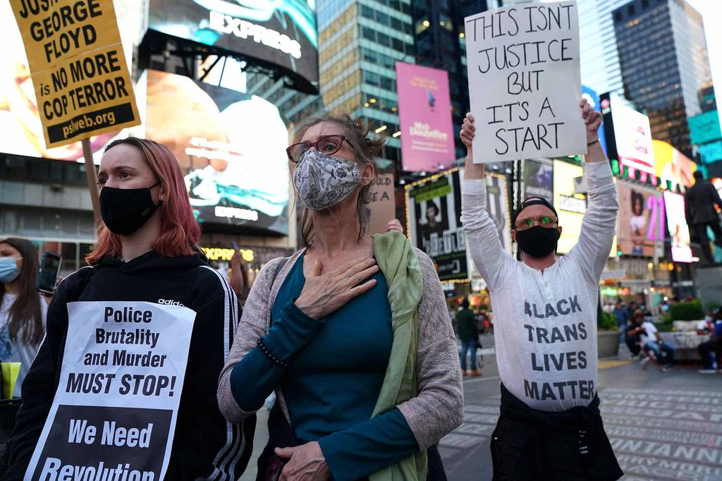 People holding signs reading 'This isn't justice but it's a start' and 'Police brutality and murder must stop! We need revolution!' rally in Times Square, New York City, following the the verdict in the Derek Chauvin trial.