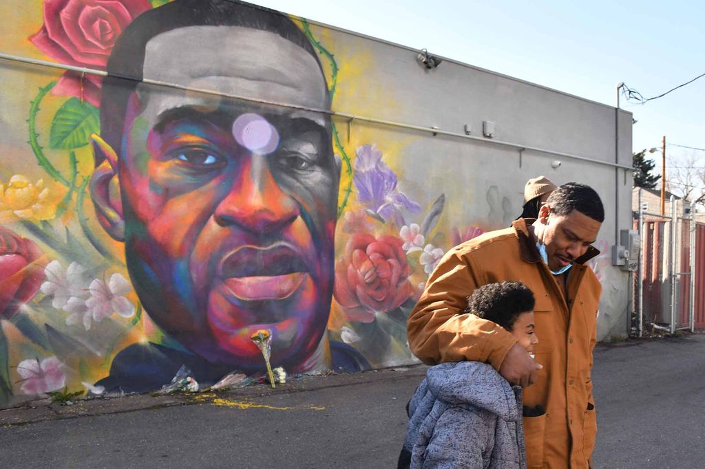 James Stapleton holds his son Kareem after they prayed for George Floyd at the mural painted by Detour and Hiero in Denver, Colorado.
