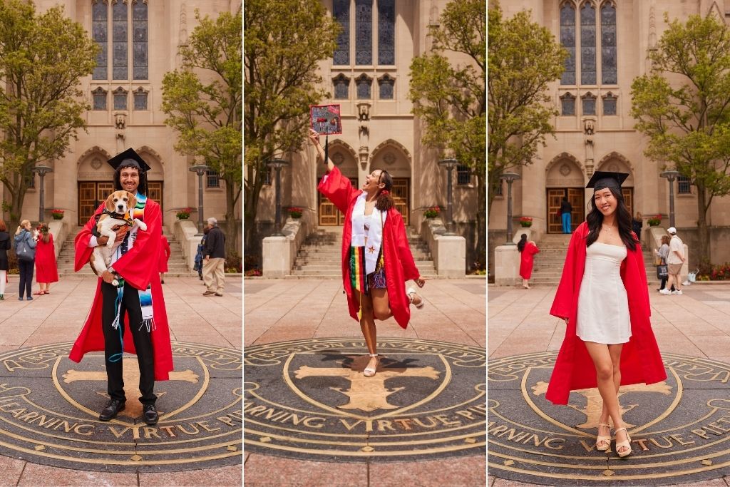 Photo: Three 波士顿大学 graduates in red gowns stand on the 波士顿大学 seal on the ground. The first graduate holds a dog, the second raises a decorated cap, and the third poses with hands on hips. All are in front of a large building with arched windows and trees.