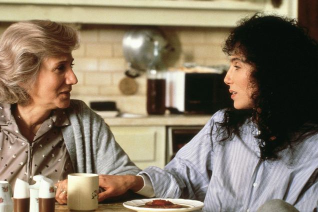 Still from the movie Moonstruck in which Dukakis, left, and Cher, converse at the kitchen table.