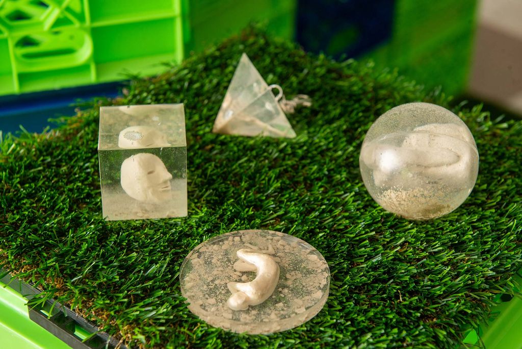 Photo of an air-dried clay and resin piece by graphic design major Emerson Lawton (CFA ‘21) for her thesis work on the commodification of tragedy. The resin pieces are beige/gold and rest on bright green astro turf.