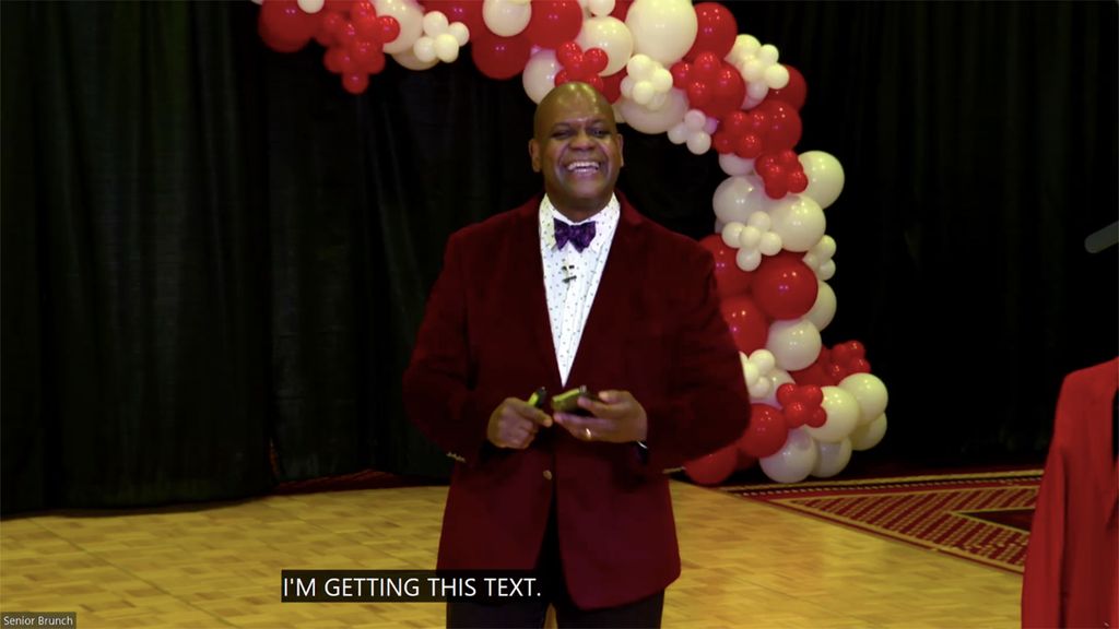 Photo of Dean Elmore smiling and looking at his phone as he receives a text asking him to wrap things up.