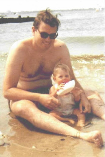 Blurry film photo of the author and her father on Jamaica Bay in Breezy Point, 1971. The baby holds her white hat in her hand.