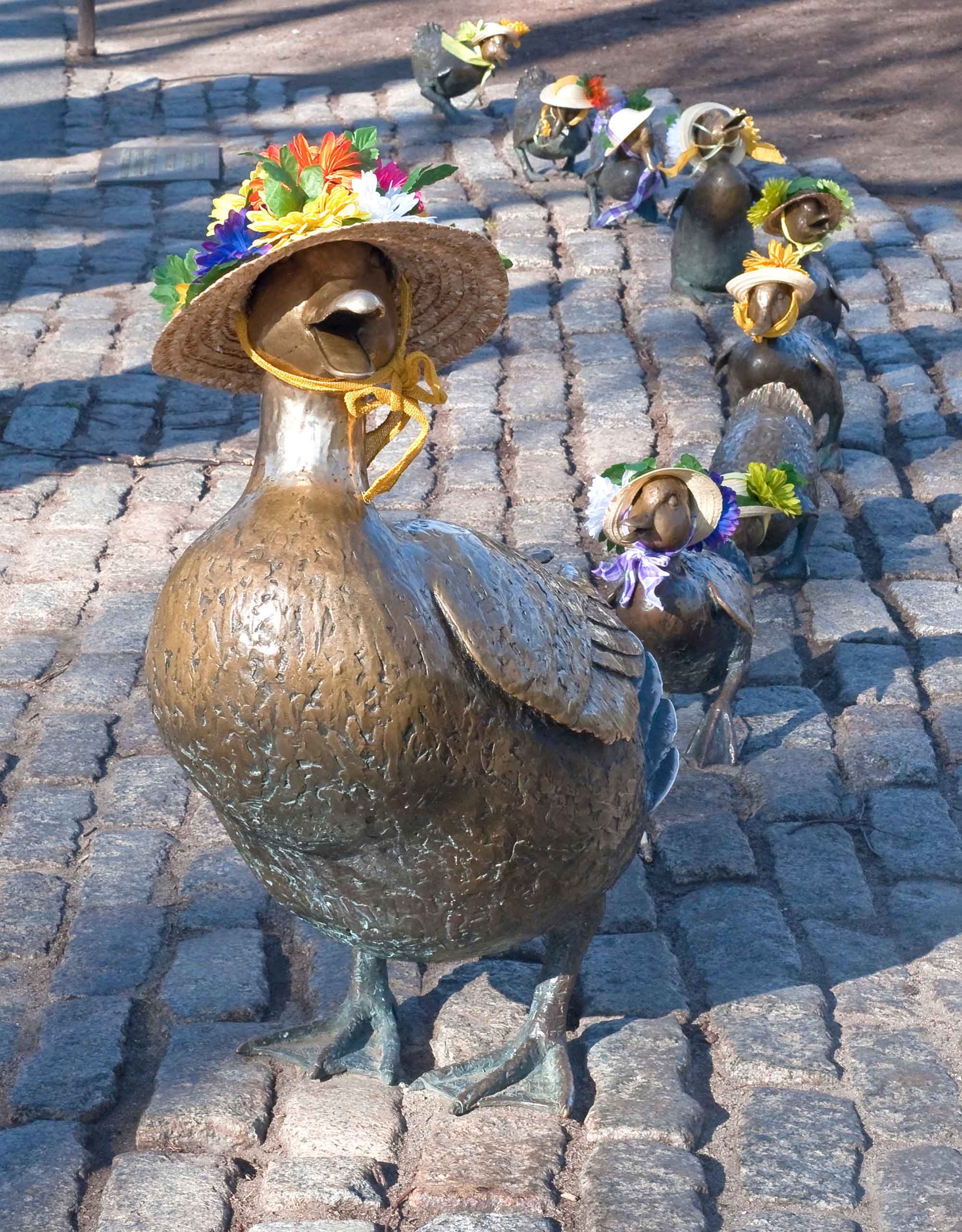 Nancy Schon's Make Way for the Ducklings sculpture in Boston decorated for Mother's Day with all ducks wearing woven sun hats with flowers.