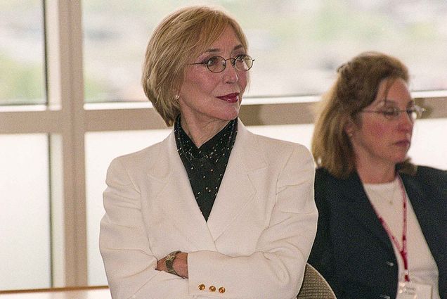 Fashion designer Jessica McClintock sits with arms crossed watching a presentation.