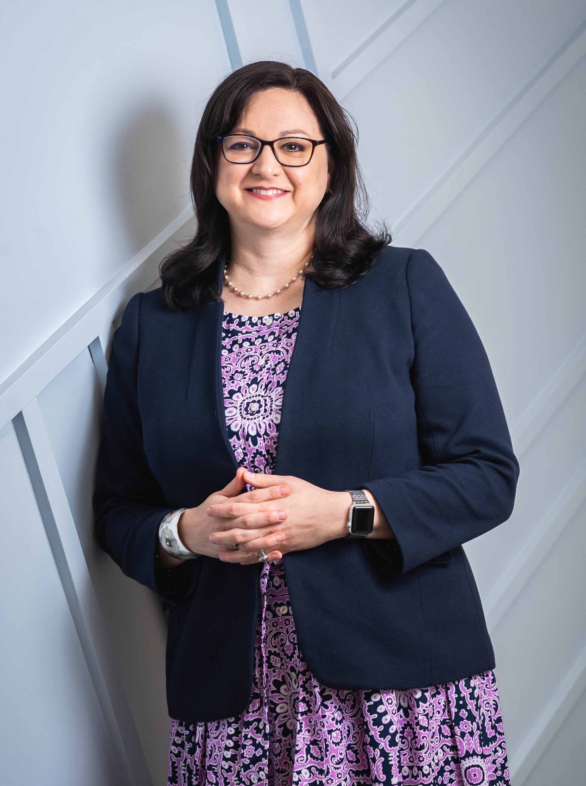 Portrait of Debbie Bazarsky, Inaugural Director of Boston University’s New LGBTQIA+ Center for Faculty & Staff, leaning against a wall in her office.