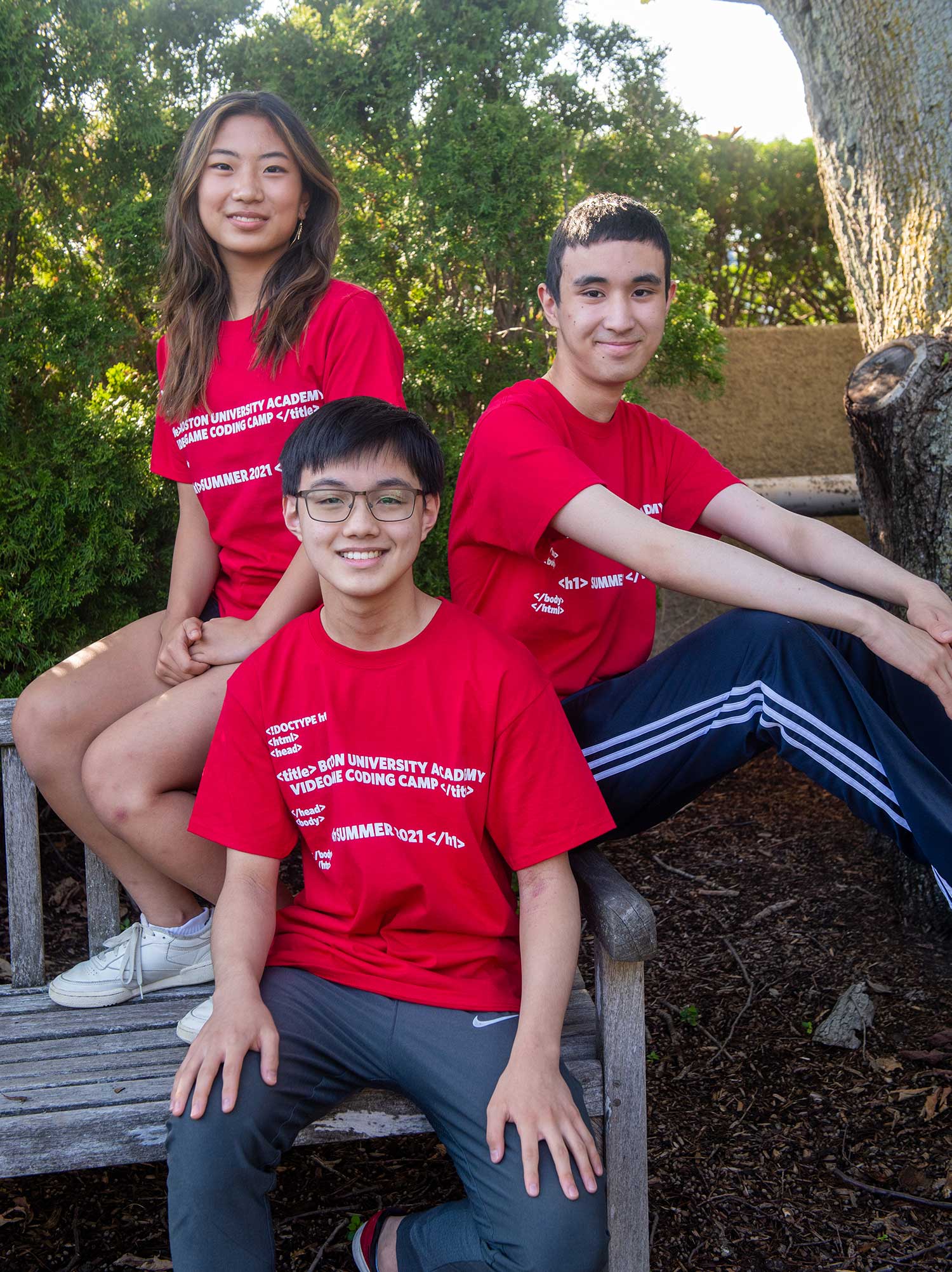 Photos of Joie Liu (from left), Alvin Lu, and Gabriel Romualdo, wearing read shirts and smiling as they sit on the edge of a park bench. Trees are seen behind them.
