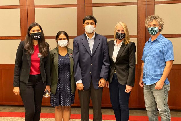 Photo of some of the winning team of Questrom’s 2021 Battle of the Boutiques. From left Rachana Krishna (Questrom’22), Bhoomika Sarur (Questrom’22 MSMS), Shreyas Srinath (Questrom’22 MSMS), Drue Hontz, principal with Saybrook Consulting Group and a consultant for the entrepreneur, Ann Marie Ronan, founder and CEO of Raybern Utility Solutions (the participating entrepreneur for this year’s competition), and Mark Arbonies, the team’s mentor and a senior consultant with Cervello. Each person wears a face mask, and everyone wears blazers, with the exception of Arbonies who wears jeans and a short-sleeve button down shirt.