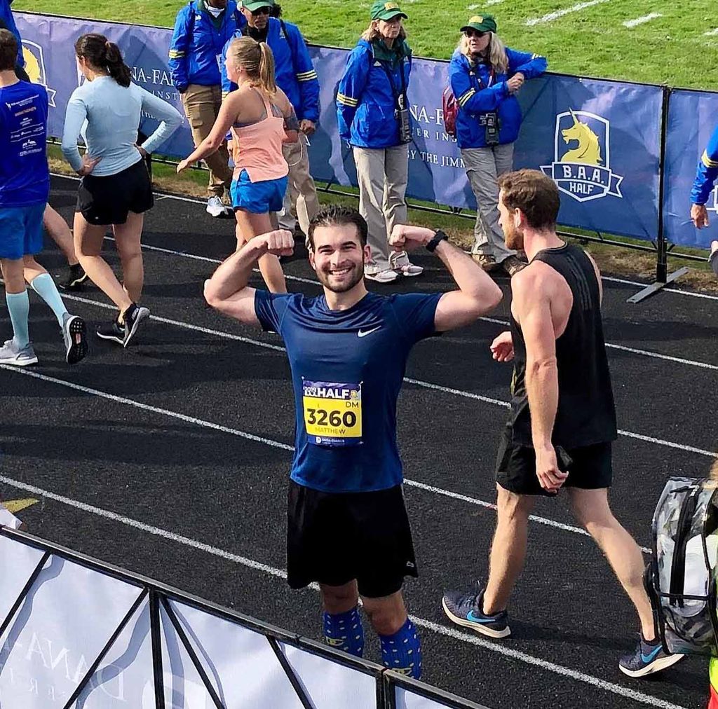 Matthew Reiss flexes his biceps for the camera after finishing the Boston Half Marathon in 2019.